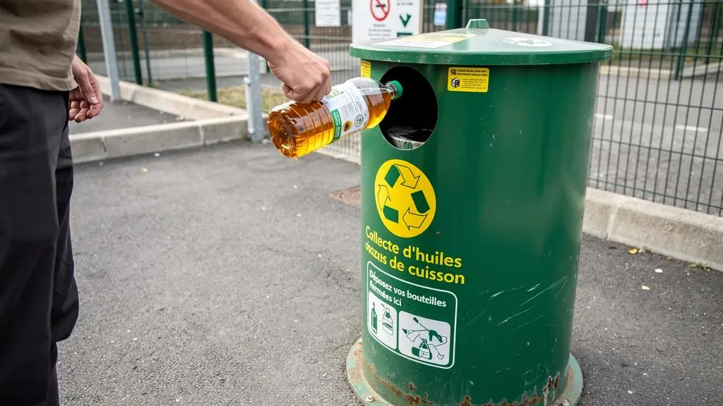 Personne déposant une bouteille d'huile alimentaire usagée dans un conteneur de collecte dédié en déchetterie