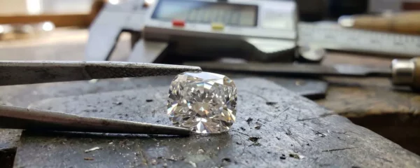 Gros plan sur une main tenant délicatement une rondelle facettée translucide en quartz rose, avec un pied à coulisse numérique visible en arrière-plan flouté, lumière naturelle latérale créant des reflets dans les facettes